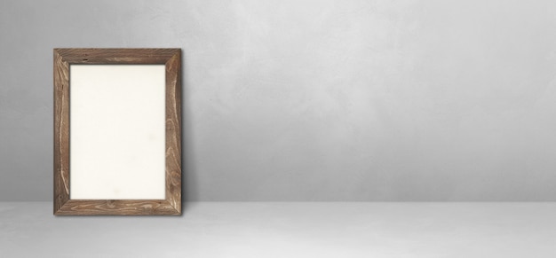 Wooden picture frame leaning on a light grey wall. Blank mockup template. Horizontal banner