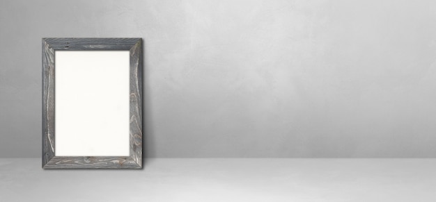 Wooden picture frame leaning on a light grey wall. Blank mockup template. Horizontal banner