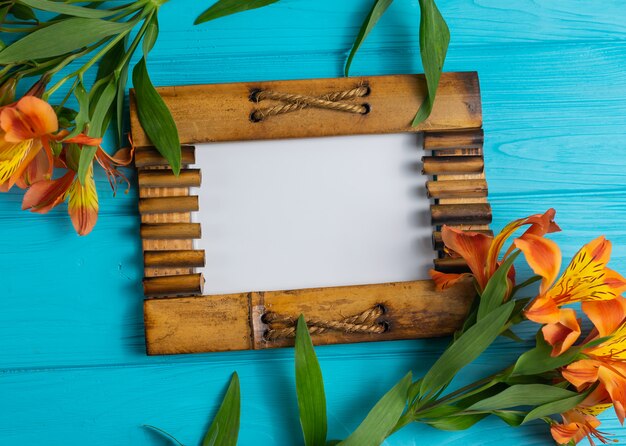 Wooden picture photo frame on blue wood with alstroemeria flowers copy space