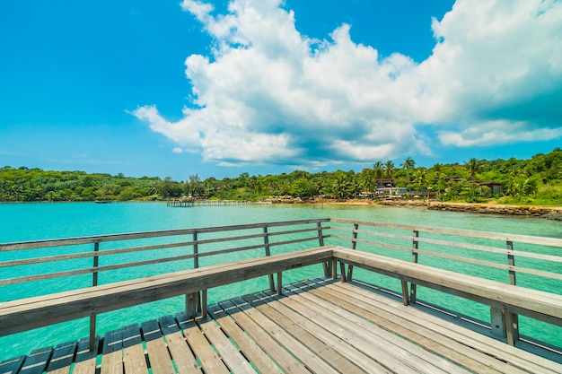 Pilastro di legno o ponte con spiaggia tropicale e mare nell'isola di paradiso