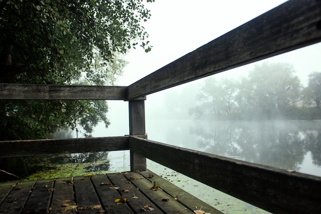 Wooden pier on a foggy river in the forest