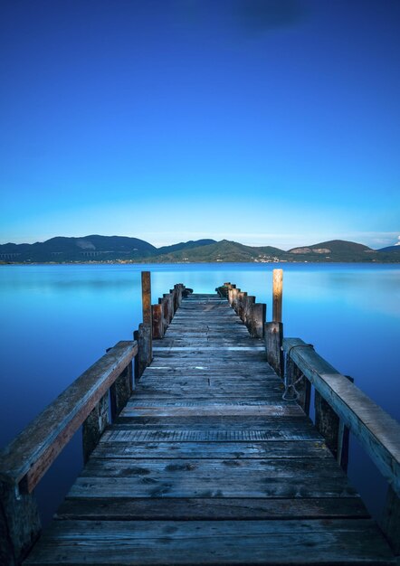 Wooden pier or jetty on a blue lake sunset and sky reflection on water Versilia Tuscany Italy