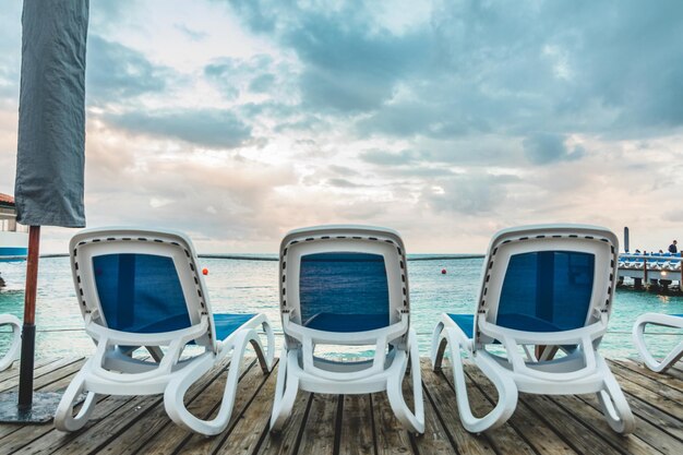 Photo wooden pier and long blue chairs with nobody