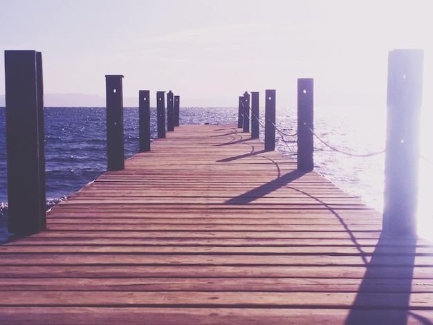 Wooden pier on sea against clear sky