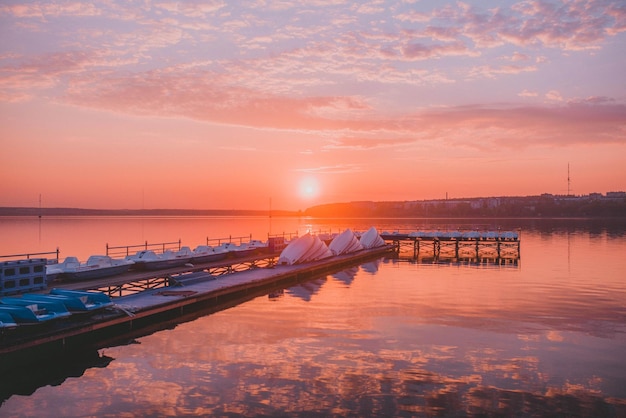 Foto molo in legno con barche al tramonto