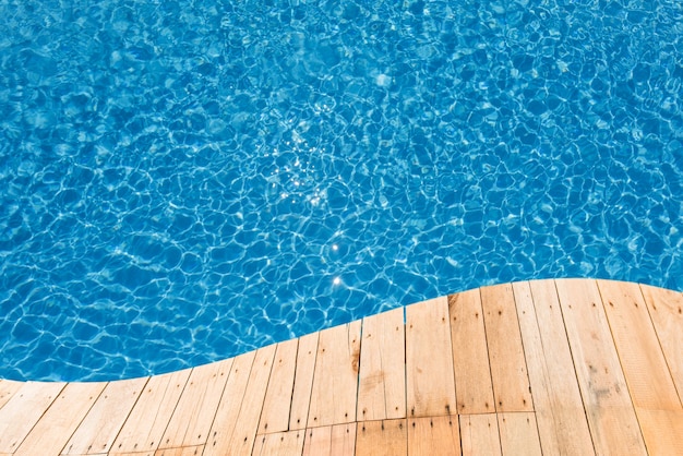 Wooden plank with blue water surface in swiimng pool