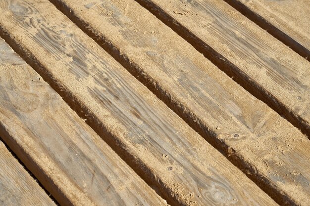 The wooden planks of the old bridge are covered with sand as a background