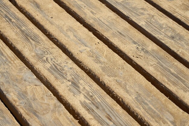 The wooden planks of the old bridge are covered with sand as a background