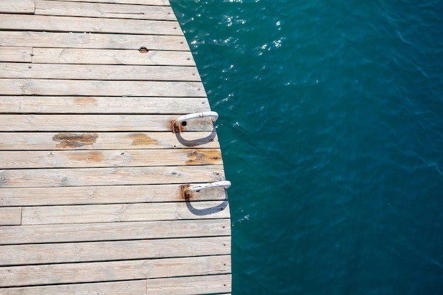 Wooden planks on the pier above the blue sea top of the water