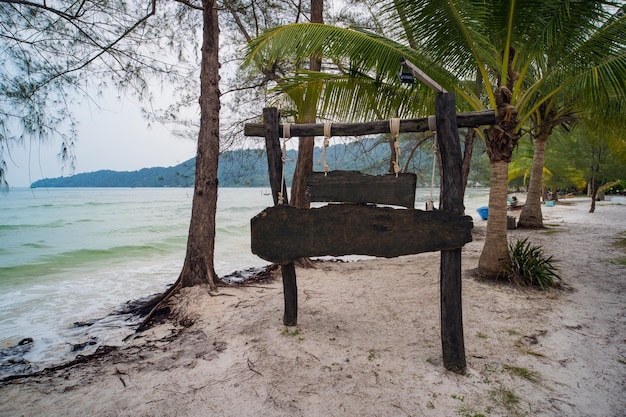 Wooden plaque on beach with palm trees Space for text Place empty for text Sales and advertising concept Travel background image