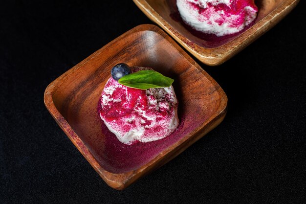 Foto piatto di legno di gelato al mirtillo con frutti di bosco freschi su fondo nero bella guarnizione colorata clouseup