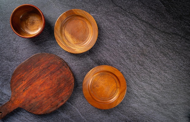 Wooden plate and chopping board on black tiles background