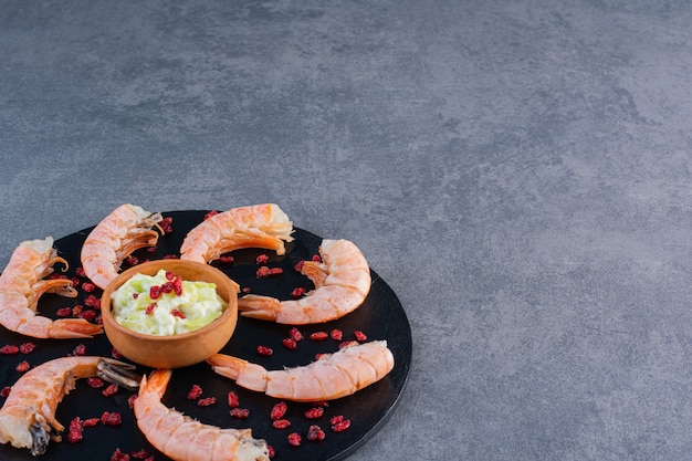 A wooden plate of delicious shrimps on a stone surface