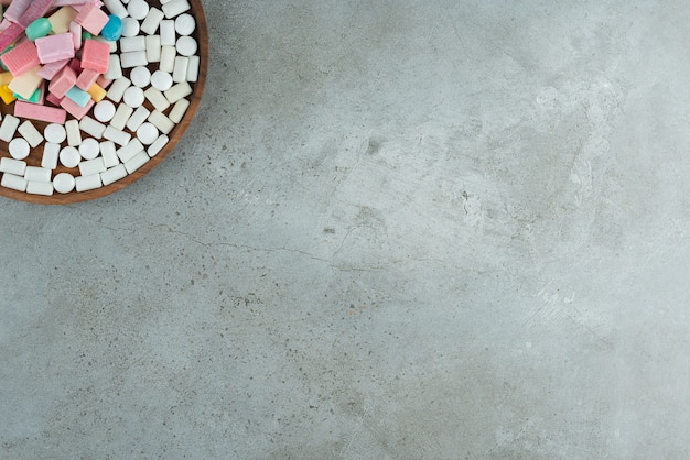 Wooden plate of many chewing gums on stone surface.