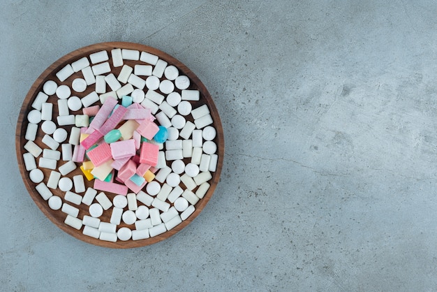 Wooden plate of many chewing gums on stone surface.