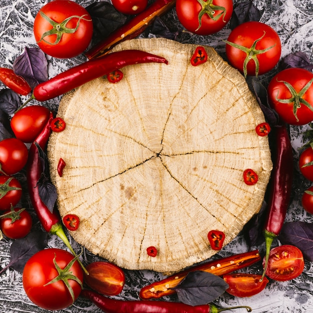 Wooden plate surrounded by chilli peppers and tomatoes