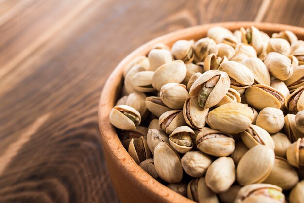 Wooden plate with pistachios on a table