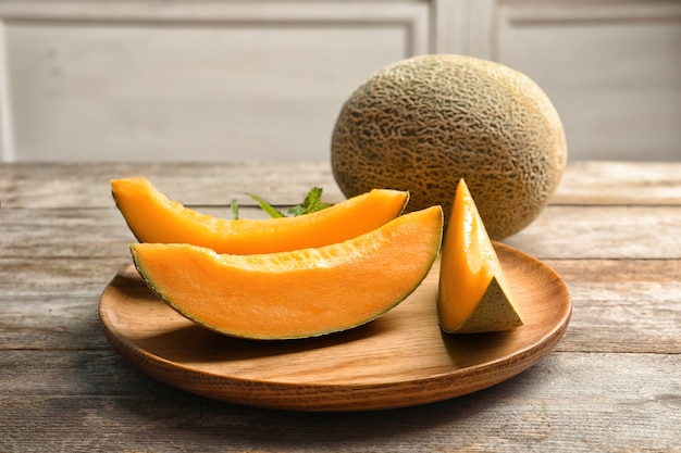 Wooden plate with sliced melon on kitchen table