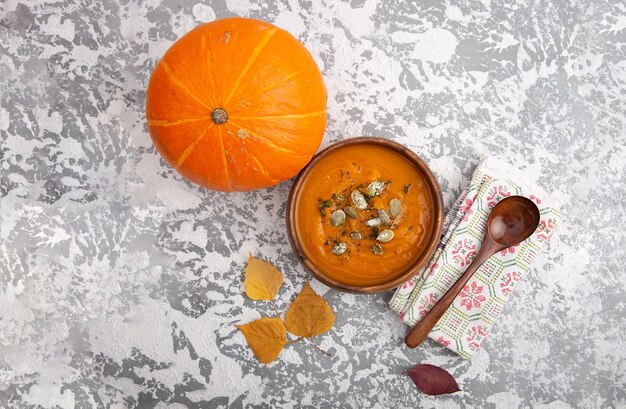 Wooden plate with soup pumpkin puree sprinkled with seeds with a wooden spoon on a rustic table. Healthy diet.