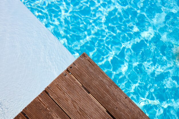 Wooden platform on swimming pool background