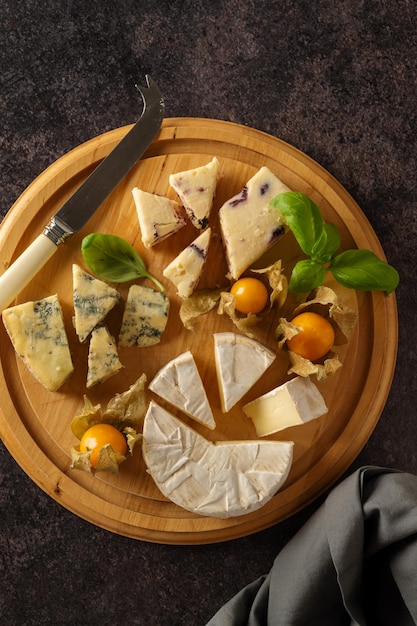 A wooden platter with cheeses and a slice of cheese.