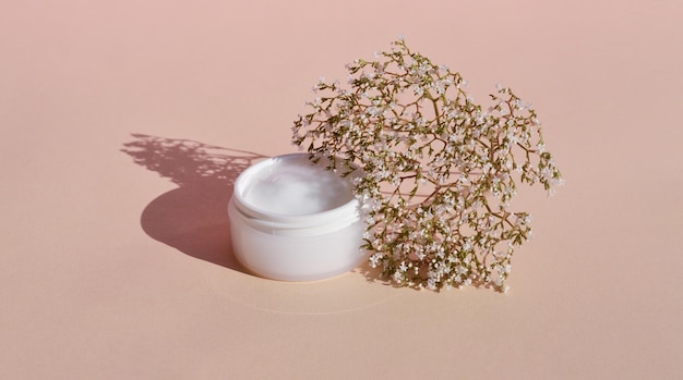 Wooden podium and dry flower with a white jar of cosmetic products