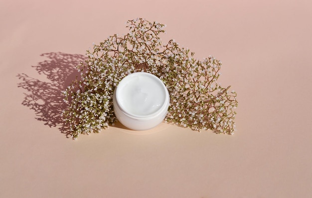 Wooden podium and dry flower with a white jar of cosmetic products