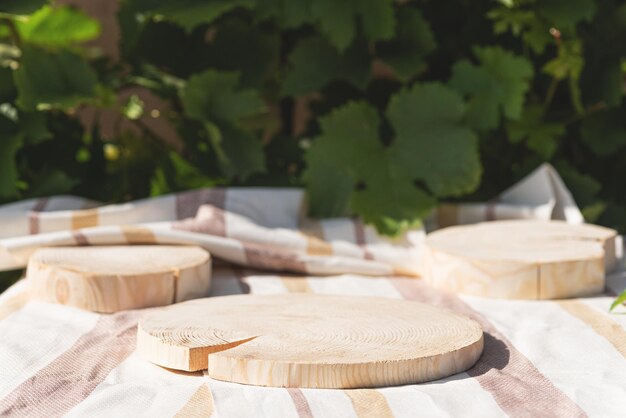 Wooden podium platform on textile towel with foliage outdoor for presentation