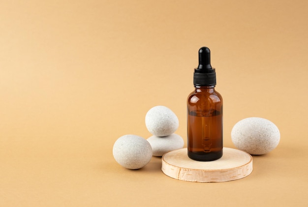 A wooden podium stones and a bottle with a pipette filled with oil or essence Body care concept natural spa cosmetics