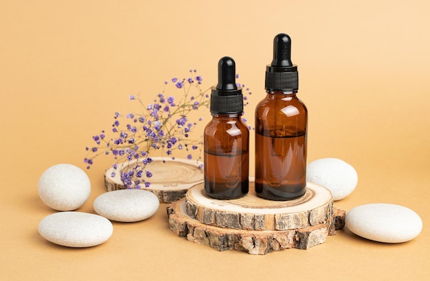 A wooden podium stones a sprig of gypsophila and two bottles with an eyedropper filled with oil or essence Body care concept natural spa cosmetics