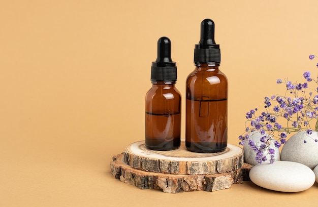 A wooden podium stones a sprig of gypsophila and two bottles with an eyedropper filled with oil or essence Body care concept natural spa cosmetics