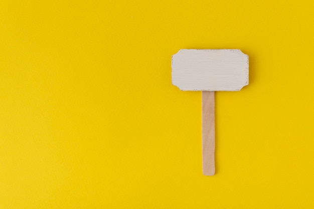 Wooden pointer on yellow background. Information plate. Wooden plate.