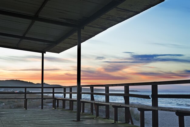 Portico in legno in riva al mare al tramonto