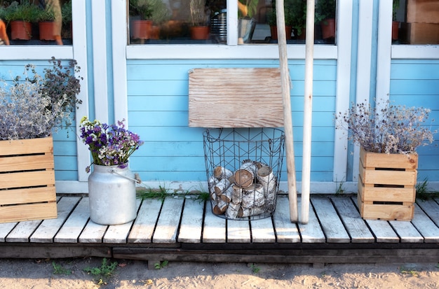 Wooden porch of house with firewood, flowers.