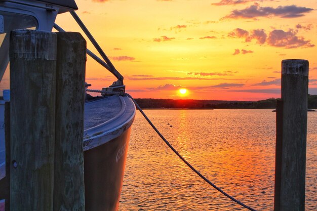 Photo wooden post by sea against sky during sunset