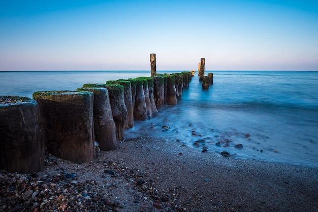 Wooden posts on beach against sky