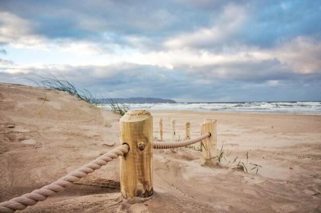 Wooden posts on beach against sky