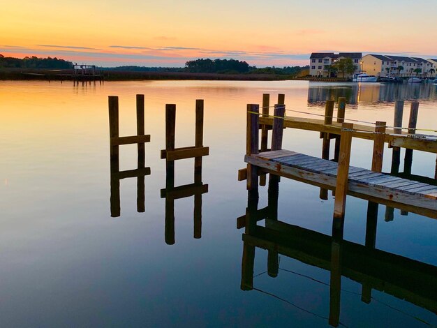 夕暮れの空に照らされた湖の木の柱