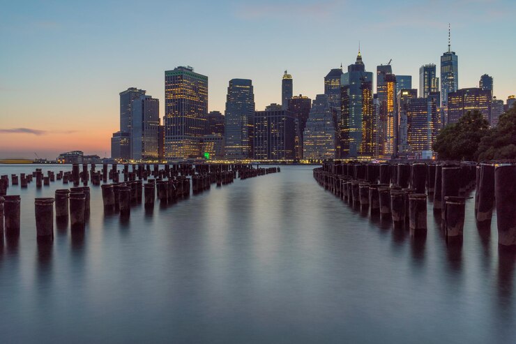 Photo wooden posts in river against modern buildings during sunset
