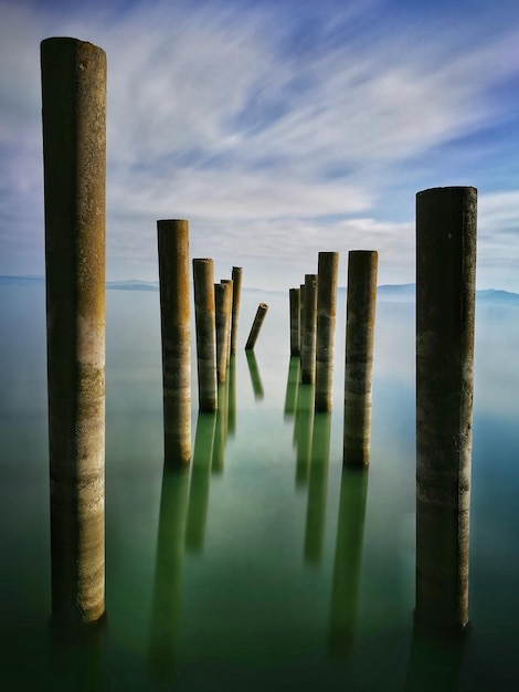 Wooden posts in sea against sky