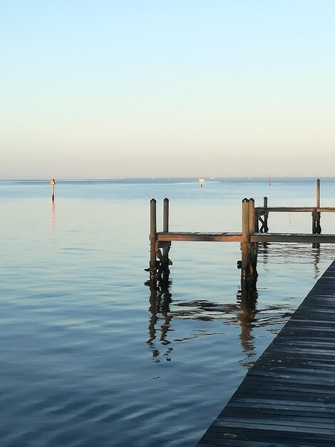 Photo wooden posts in sea against sky