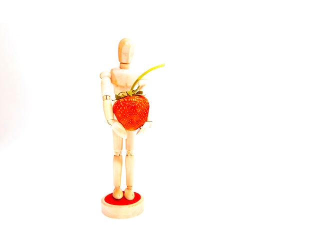 Wooden puppet holding a big strawberry