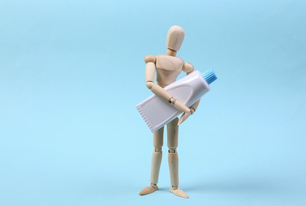 Wooden puppet holding cream tube on blue background