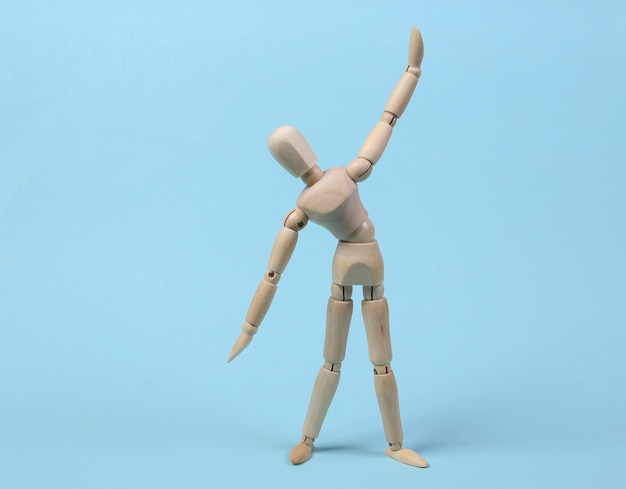 Wooden puppet practicing aerobics on blue background