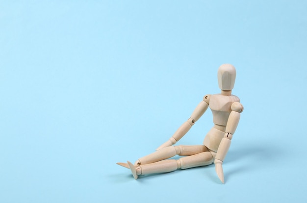 Wooden puppet sits isolated on blue background