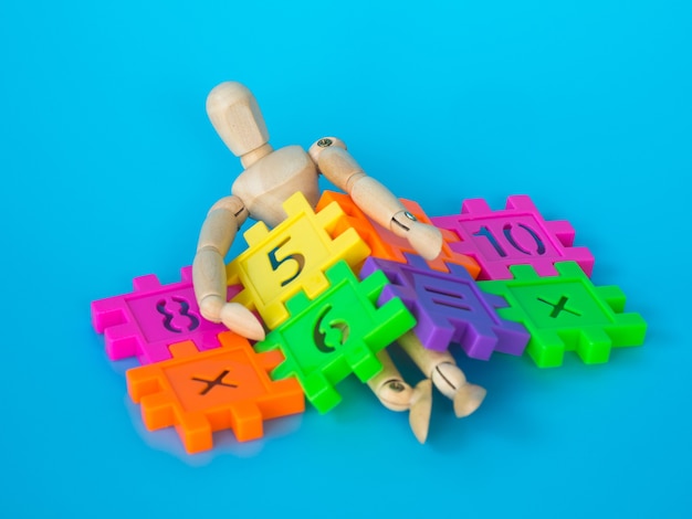 Photo wooden puppet sleep in colorful plastic number on blue background