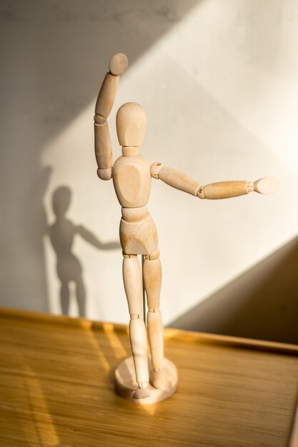 Wooden puppet stay under the table dancing pose closeup view