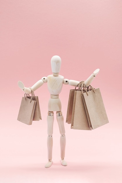 Wooden puppet with craft paper shopping bags sale or shopping
concept