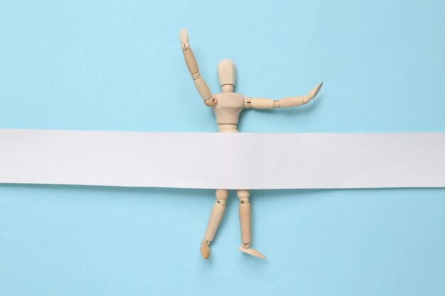 Photo wooden puppet with a white ribbon on a blue background winner concept