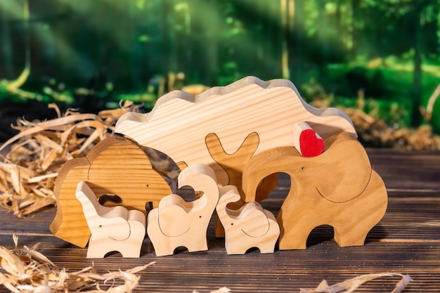 Wooden puzzle in the form of a family of handmade elephants on the background of the forest